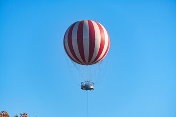 A hot air balloon as a viewing platform for tourists is flying high in the sky above the treetops in Budapest, Hungary.