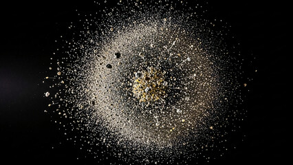 a pile of white and gold glitter on a black background