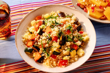 Moroccan vegetable couscous served with citrus salad on a colorful striped tablecloth