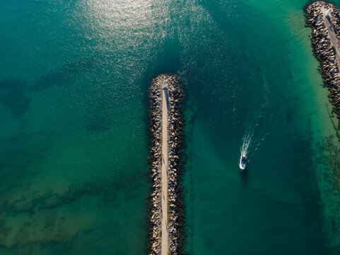 Aerial view of a boat cruising along the Mooloolaba River mouth, with the sun reflecting off the water, Mooloolaba, Queensland, Australia.