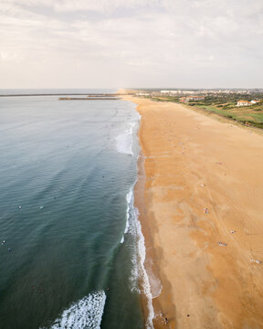 Aerial view of golden sands meeting the turquoise waves under a soft sky, creating a serene coastal panorama, Anglet, Nouvelle-Aquitaine, France.