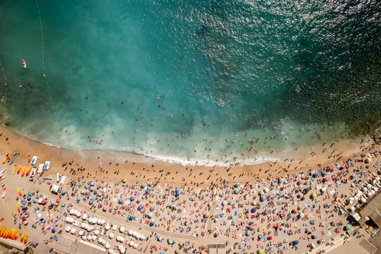 Aerial view of a vibrant beach teeming with people, colorful umbrellas dotting the golden sand meeting the turquoise sea, Cassis, Provence-Alpes-Cote d Azur, France.