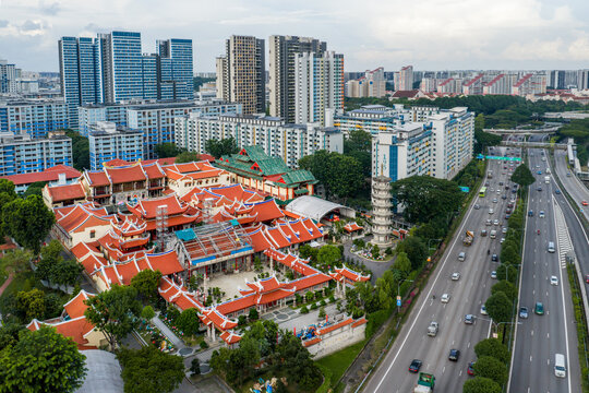 Aerial view of the vibrant red roofs of the Lian Shan Shuang Lin Monastery contrast against the modern cityscape, Singapore, Singapore.