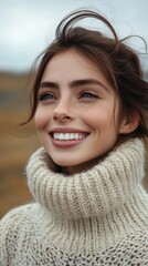 A woman with a smile on her face is wearing a white sweater. She has a pixie cut and is wearing a necklace