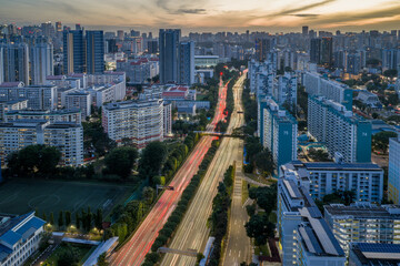 Aerial view of a vibrant cityscape with blurred streaks of traffic bisecting rows of buildings, as twilight descends over Toa Payoh, Singapore, Singapore.
