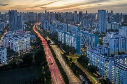 Aerial view of the Pan Island Expressway slicing through Toa Payoh, the streaks of car lights painting vivid lines between the towering buildings, Singapore, Singapore.