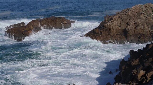 Foamy Waves Breaking Against The Rocks Of The Senda Azul (Paseo Mar&iacute;timo de Arteixo) In Arteixo, A Coru&ntilde;a, Spain. Aerial Pullback Shot