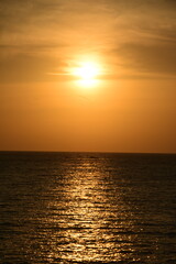 Fototapeta premium A breathtaking tropical seascape during the golden hour or sunset, featuring a dramatic sun flare and long, bright reflection path across the ocean surface