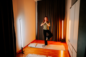 Young woman practices yoga at home in evening light with focus on posture