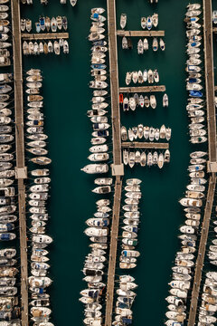 Aerial view of numerous boats docked neatly in parallel rows, creating a mesmerizing pattern against the deep turquoise water of the marina, Menton, Provence-Alpes-Cote d'Azur, France.