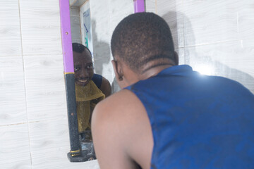 man drying his face with a towel while looking at his reflection in the bathroom mirror.