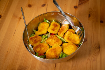 Salad with Nuggets in Chrome Bowl on Wooden Table