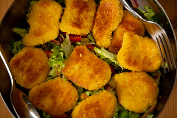 Salad with Nuggets in Chrome Bowl on Wooden Table