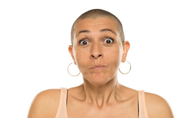 Studio shot of bald woman in tank top with surprised facial expression on white background.