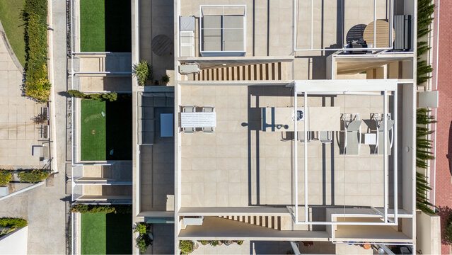 Modern rooftop terrace with outdoor dining and sun loungers in a contemporary apartment complex