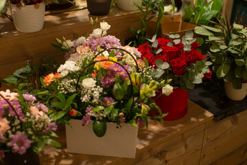 vibrant flower shop display on wooden counter, assorted bouquets, pots, and greenery lined up for browsing, warm market atmosphere