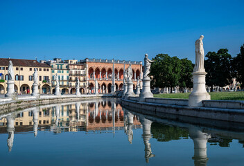 Padua, Italy. Pratto della Valle square with two rows of statues (late 18th century), an oval-shaped canal, and bridges. Early morning, no people, reflection in the water.