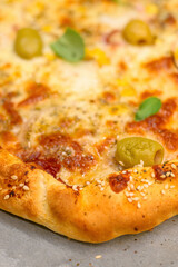 Baked cheese pizza with olives, herbs, and golden crust on parchment paper.