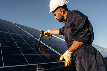 Crystal clear surface, installation, using tool. Male solar engineer examining photovoltaic panels at a power station