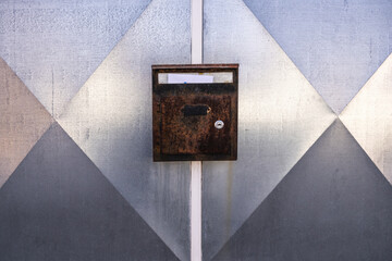 Rusty old mailbox with letter on metallic gate
