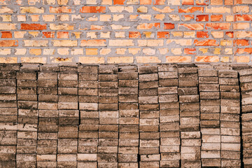 Weathered concrete slab blocks stacked in front of a vintage brick wall, construction renovation projects background.