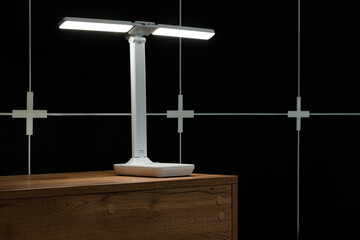 still life scene of black interior studio design nightstand electric lamp and black cell panels...