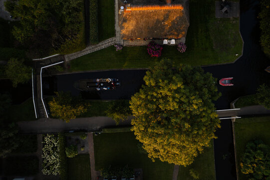 Aerial view of boats navigate the canals, reflecting the sky, with lush greenery and thatched roofs creating a tapestry of textures, Giethoorn, Overijssel, Netherlands.