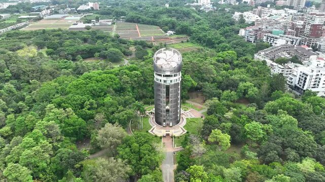 Aerial view of Sun-Shooting Tower in Chiayi Park, Taiwan. Iconic cylindrical landmark architecture with aluminum facade mimicking Alishan sacred tree. 4K Drone