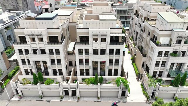 Aerial pull back revealing luxury neoclassical townhouse community in Chiayi, Taiwan, with modern stone facade residential villas, 4K drone shot.