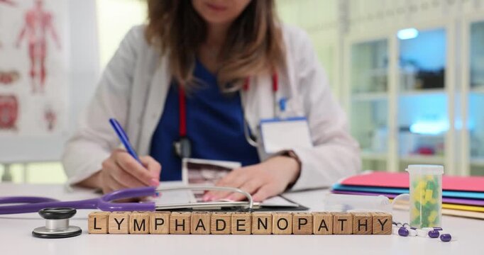 Wooden blocks on table spell word Lymphadenopathy near stethoscope. Woman doctor checks scan images writing note about swollen nodes at appointment