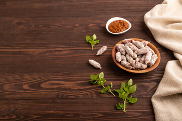 Small smoked Chicken sausages in wooden bowl on brown wooden. side view, copy space