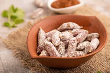 Small smoked Chicken sausages in clay bowl on brown concrete. side view, close up, selective focus