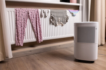 collecting moisture with dehumidifier while drying laundry on the radiator at home. air humidity...
