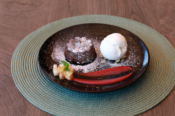 Chocolate lava cake dessert with scoop of vanilla ice cream and fruit garnish