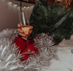 Retro-style photo of legs, red tights, tinsel, and a glass of champagne. Christmas concept.