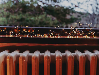 Photo of a window with a view of the forest, a windowsill with a Christmas garland and a retro cast...