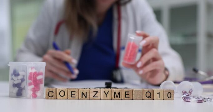 Text Coenzyme Q10 on wooden blocks with scattered color capsules on doctor desk. Ubiquinone naturally occurring biochemical cofactor and antioxidant
