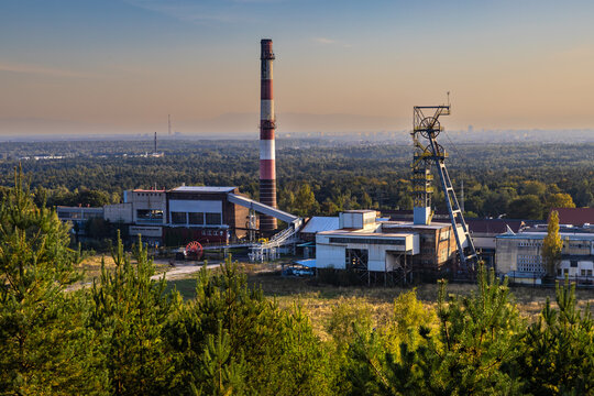 The buildings, chimney and shaft tower of the disused Boże Dary mine illuminated by the setting sun. Kostuchna, Katowice, Silesia, Poland