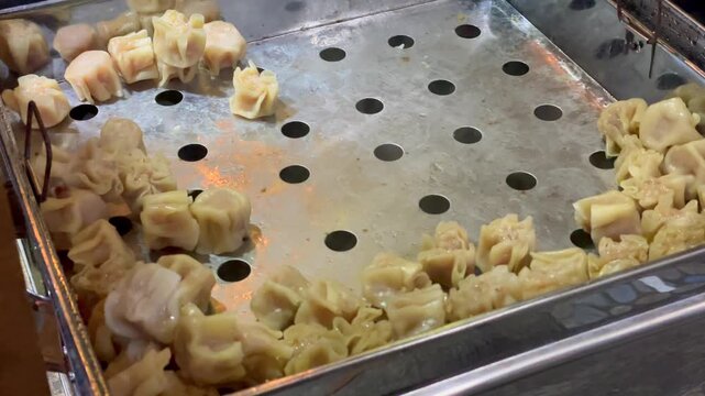 Close up of steamed dimsum shumai served in a stainless steel steamer tray at a buffet.