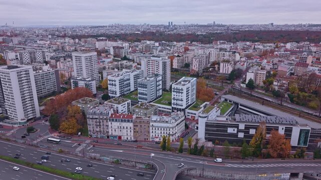 Aerial drone view of Saint-Maurice suburbs near Paris. Features highway traffic, high-rise apartments, a soccer field, and the Bois de Vincennes in autumn. Ideal for urban planning concepts