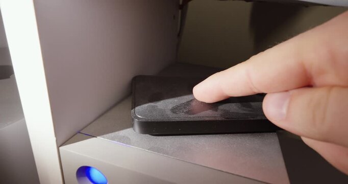 Close-up of a dusty external hard drive on an office desk as a finger wipes across the surface, highlighting dust accumulation, neglect, workplace hygiene, and everyday technology use.