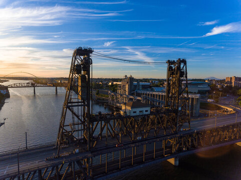 Aerial view of the Broadway Bridge and the Willamette River create a striking contrast against the urban landscape under a vast sky, Portland, Oregon, United States.