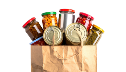 A brown paper bag overflows with various jars and cans of preserved food items