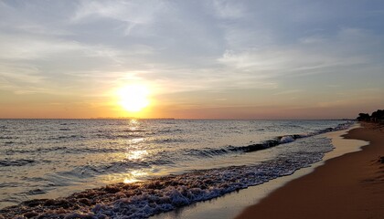 Golden ocean sunset washes over a tranquil sandy beach shoreline at dusk