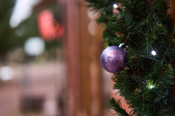 CloseUp Purple Bauble On Garland Soft Bokeh Lights, Warm Wood Storefront, Glitter Texture, Cozy Holiday