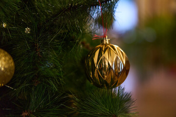 gold ornament with tassel on branch, hotel lobby styled for elegant holiday reception, soft bokeh lighting, polished surface