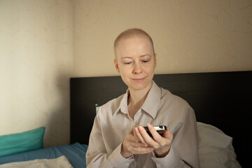 Woman after chemotherapy looking at smartphone with gentle smile, concept of hope, resilience, and support network.