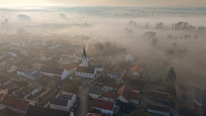 Foggy Bavarian landscape during morning sunrise phase with forest background and small village close which is called P&ouml;rnbach and is located at the region of Pfaffenhofen