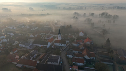 Foggy Bavarian landscape during morning sunrise phase with forest background and small village close which is called P&ouml;rnbach and is located at the region of Pfaffenhofen