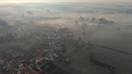 Foggy Bavarian landscape during morning sunrise phase with forest background and small village close which is called P&ouml;rnbach and is located at the region of Pfaffenhofen